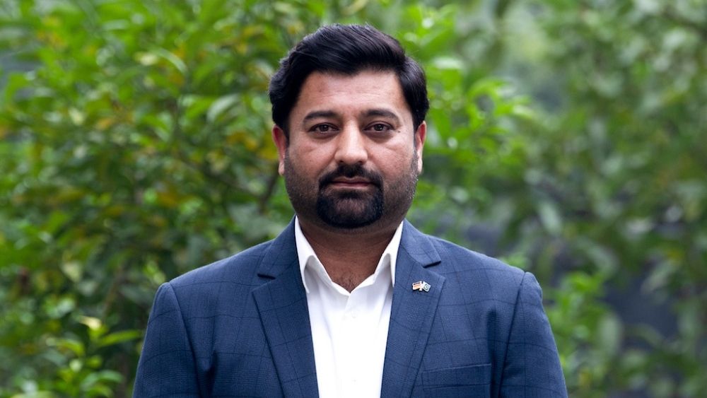 Ein Mann steht vor einer Hecke und schaut in die Kamera. Es ist Dr. Khan, der Leiter des Beratungszentrums.