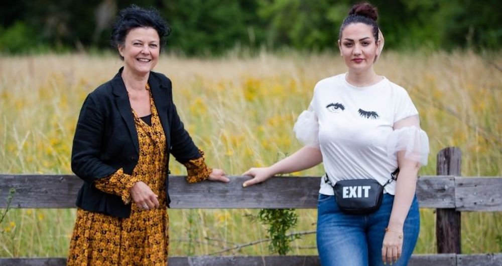Zwei Frauen stehen an einem Zaun