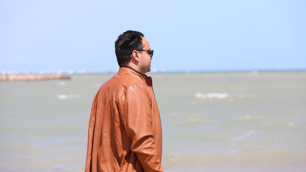  يقف رجل على الشاطئ وينظر إلى الماء.
