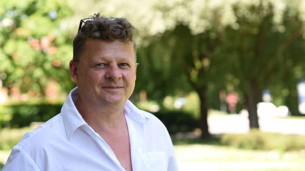 Ein Mann mit weißem Hemd und einer auf den Kopf geschobenen Brille blickt in die Kamera.