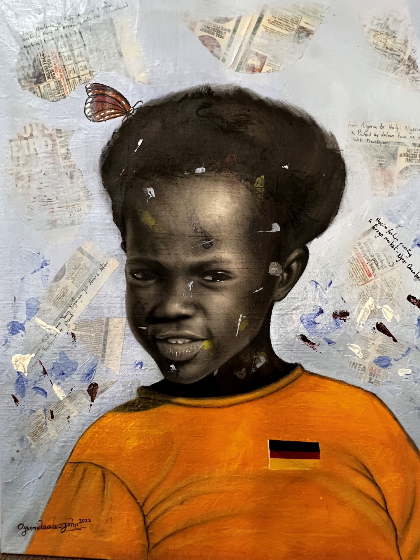 Auf der Leinwand ist ein juges Kind mit schwarzen Haaren zu sehen. Es trägt ein orangefarbenes T-Shirt, auf dem eine kleine Deutschland-Flagge zu sehen ist. Auf dem Kopf des Kindes sitzt ein Schmetterling.