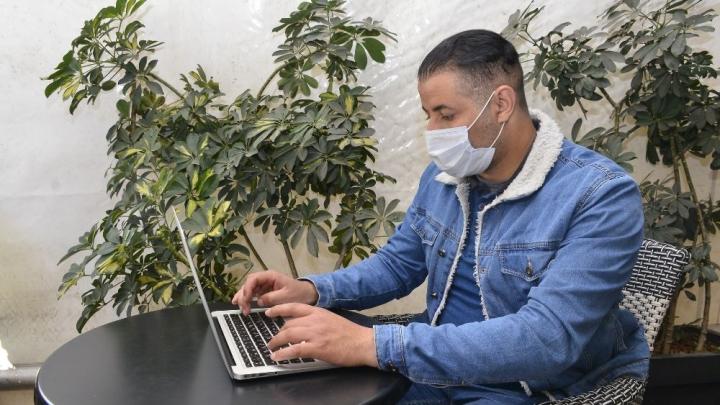 Ein Mann sitzt an einem Tisch und arbeitet am Laptop.