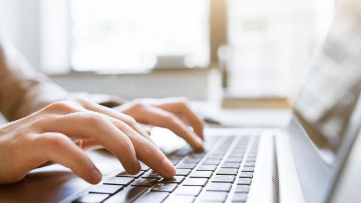Zwei Hände tippen etwas auf einer Computer-Tastatur.