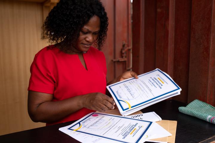 Eine junge Frau hält Papiere in der Hand, darauf steht in Englisch Zertifikat.