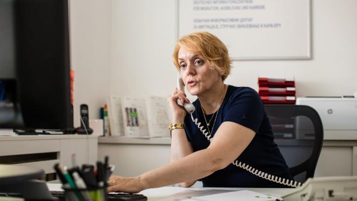 Eine Frau sitzt an einem Schreibtisch und bedient das Telefon
