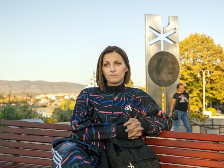 Terapeutkinja Jelena stoji ispred banera sa logotipom dveju organizacija, od kojih je primila podršku.
