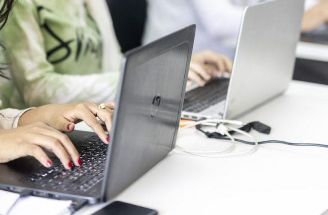  Weibliche Hände tippen auf der Tastatur eines schwarzen Laptops. 
