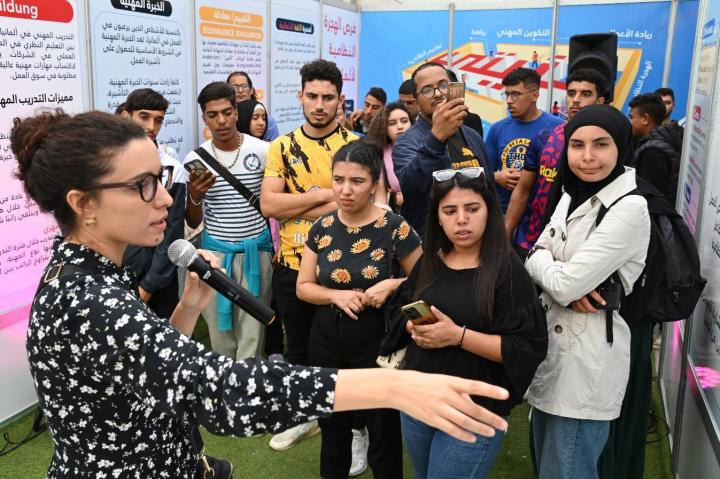  A young woman with a microphone speaks to a group of people 